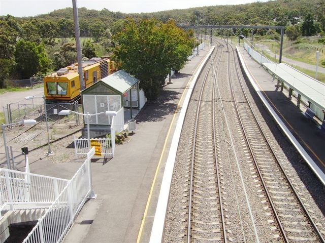 A view looking towards Sydney shows a rake of track maintenance vehicles are stabled on the remnant of the Wangi Wangi branch at Awaba Station. This siding which is now cut back to a couple of hundred metres has a pedestrian crossing for station access.