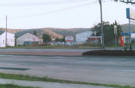 The location where the Gosford Racecourse branch line used to cross the Pacific Highway. The line swung to the right of the large shed (originally the Gosford Cold Store, now Singletons Butchers) in background. The rail line was removed in 1993 when the Pacific Highway was widened from two to six lanes.