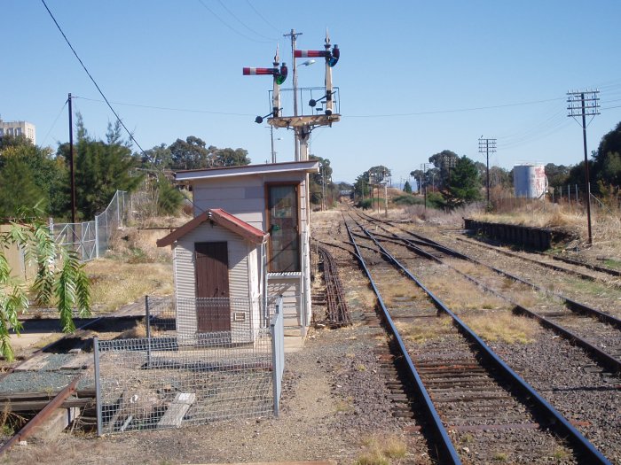 The view looking down the line beyond the station. The small cabin encloses the F Frame. The signals control the former main line to Bombala (left) and the branch line to Canberra (right). On the far right is the remains of the stock loading platform.