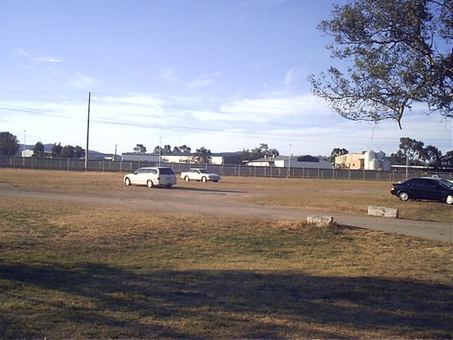 The view looking looking from the racecourse carpark. The platform location is approximately behind the far white car. Racegoers would have walked across to the meetings. In the background are the warehouses of the North Albury industrial estate. 