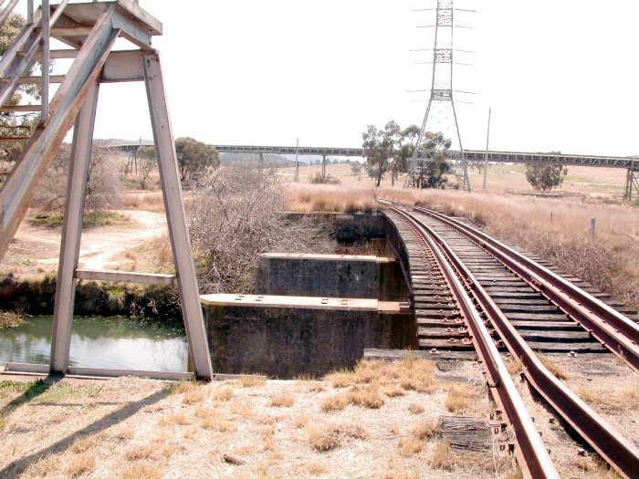 The view looking north from the north junction.  The bridge over the creek was clearly constructed for double tracks. The elevated structure is a coal conveyor belt.