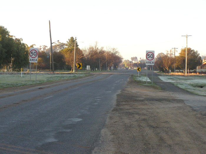 Jerilderie Street (Main Road No. 564) looking south. The little hump in the road with the arrows marks the former site of the level crossing with the Tocumwal Branch, just south of Berrigan Station.