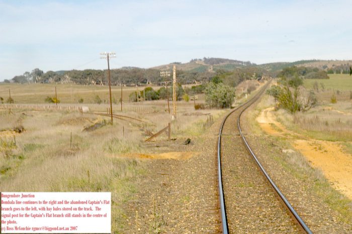 The Bombala line continues to the right and the abandoned Captains Flat branch goes to the left, with hay bales stored on the track. The signal post for the Captains Flat branch still stands in the centre of the photo.