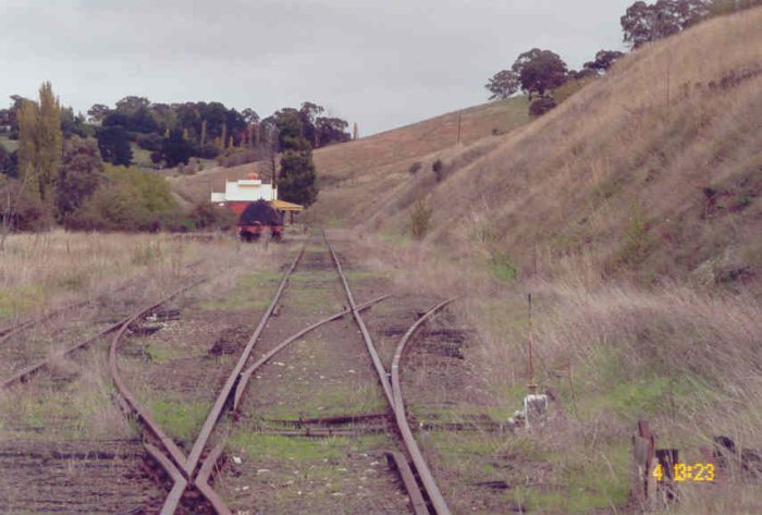 The view looking south towards the station.  On the left is the goods siding, with an abandoned water gin. The former goods shed was on the far left.  The siding on the right is the overgrown loop siding.