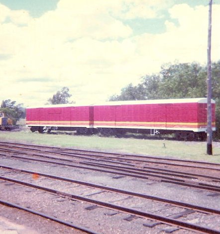 Candy-liveried louvred wagons sit in a siding.