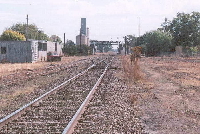 A line-side view from next to the main south, looking north to the footbridge and silos in the distance.