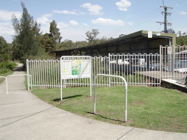 The former branch to Toronto is still largely intact  despite the platform being filled in. The curved platform and shelter was where terminating 2 or 3 car electric sets would meet with the 2 car diesel shuttle that operated the Toronto - Fassifern service. The rails for the line to Toronto and the storage siding are still in place in the long grass behind the white fence. The "V" shaped Fassifern platforn servicing the Up Line is to the right of the camera. The concrete path for pedestrians and bicycles follows the railway right-of-way to Toronto.