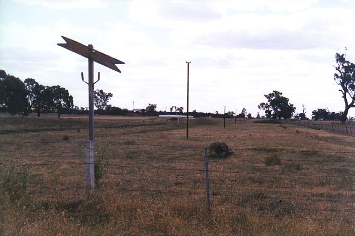 
The remains of a level-crossing sign and telegraph poles.  The station lies
behind the first pole.
