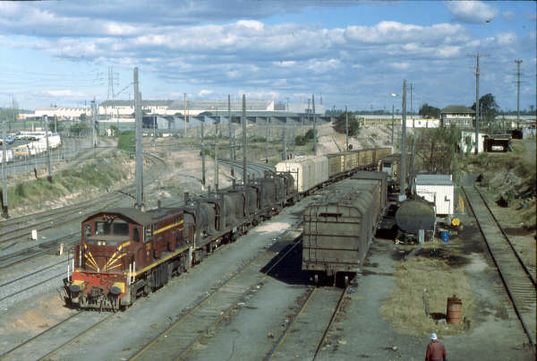 7321 heads toward Pippita with a local freight to do some shunting with Flemington Goods Jct. Signal Box in the background, perched on its high vantage point.