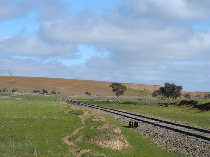 The view looking south towards the location. The station was located on the left of the line, with the ruins in the distance being the location of the goods and grain sheds.  The structure in the foreground is likely the base of the B Lever Frame.