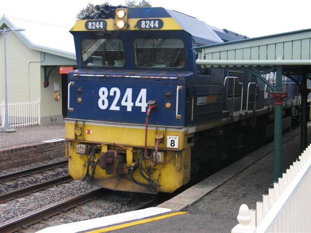 
8224 at the head of a load coal train dwarfs the station building.
