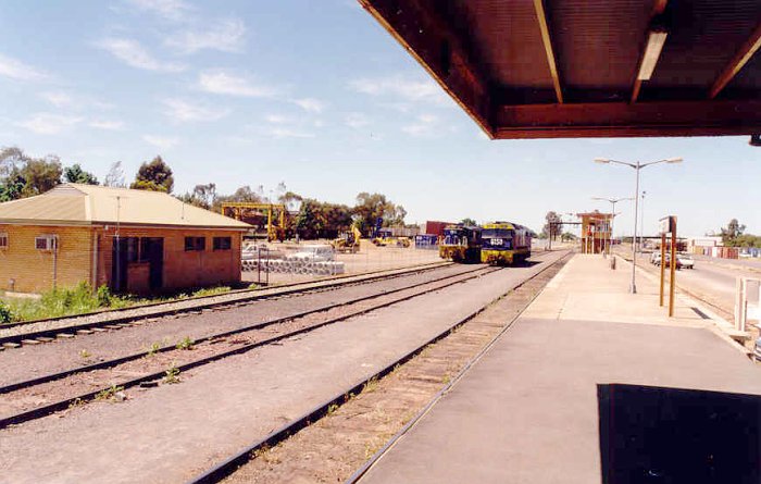 The view looking along the platform in an up direction. The sidings on the left are the No 1 goods siding and loop line. On the right of the platform is the obscured back platform road. The signal box is visible at the end of the station.