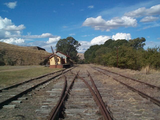 
The view in the yard looking in the up direction, showing the goods shed
and job crane.  The structure on the hill is a water tank.
