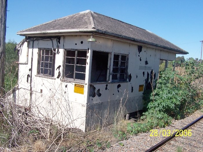 A closer view of the old Newdell Signal Box, showing its dilapidated state and asbestos warning signs.