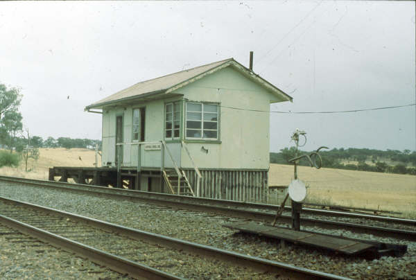 Kapooka Signal Box sat off the main road and was rather an isolated box but was an important crossing point. This 1980 photo shows an automatic staff exchanger ready for an up train to Wagga. The staff was placed in the top ring for collection by the locomotive while the bottom "rams horn" took the staff from the Uranquinty section, all at speed.