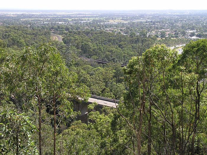
The view looking down over the Knapsack bridge, the original rail
bridge, with the current railway bridge in the distance.  The freeway
is visible beyond the trees in the left foreground.
