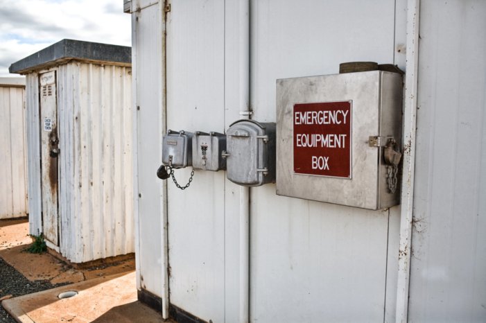 Telephone and emergency equipment mounted outside one of the huts at the location.