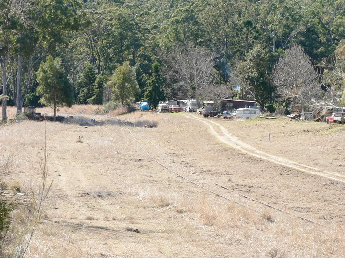 The view looking up the line through the location. The station was located on the right of the track next to the straight section in the centre of frame. The flat area opposite was used for loading logs from the adjacent sawmill.