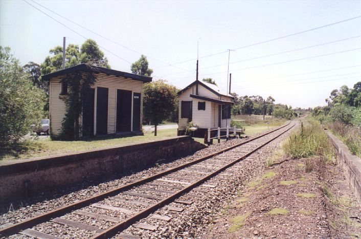 
The view of Neath's down platform, showing the small toilet/storage block
and the signal box, which controlled the Neath Colliery branch.  This
branch left the main line on the middle background, and crossed the
road just behind the platform.
