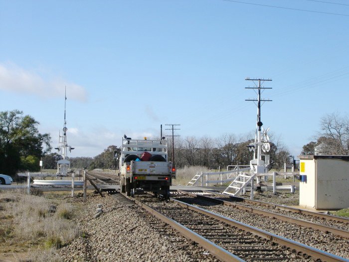 A hi-rail truck heads passes the level crossing at the up end of the location, heading towards Sydney.