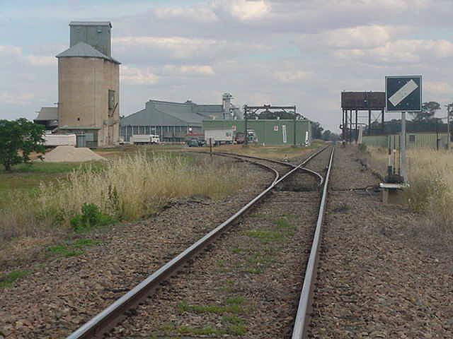 
The view looking south to the silo siding.  Note the presence of the
gantry crane and large elevated water tank.  The station was located
just beyond the tank, on the same side of the line.
