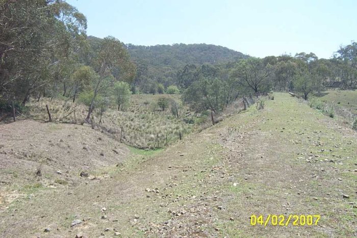 To the left of the photo is a siding off the main line, possibly a construction siding for the bridge. On the other side of the bridge is another siding leading up to the bridge also a flat area where there might have been a platform, behind this area again is a very flat area where the construction workers might have pitched their tents.