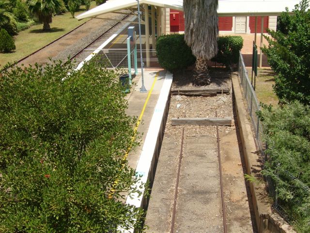 The dock platform and track as viewed from the footbridge. Although it appears to be out-of-use, the associated points, catch point and  ground lever frame seem to be intact (behind the photographer).