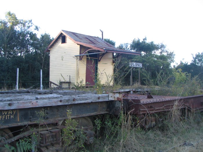 Vegetation grows among abandoned wagons at Ulong station.  The line from Glenreagh approaches from the right.